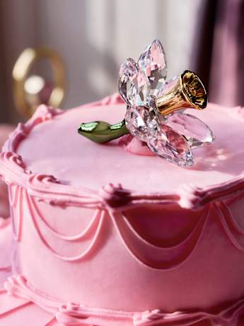 Swarovskiクリスタルのフラワーデコレーションが上部にあしらわれた、ピンクのケーキ。