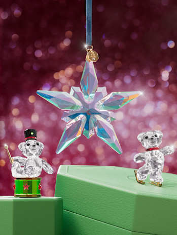 Two Swarovski crystal ornaments and two bear figurines on green gift boxes.