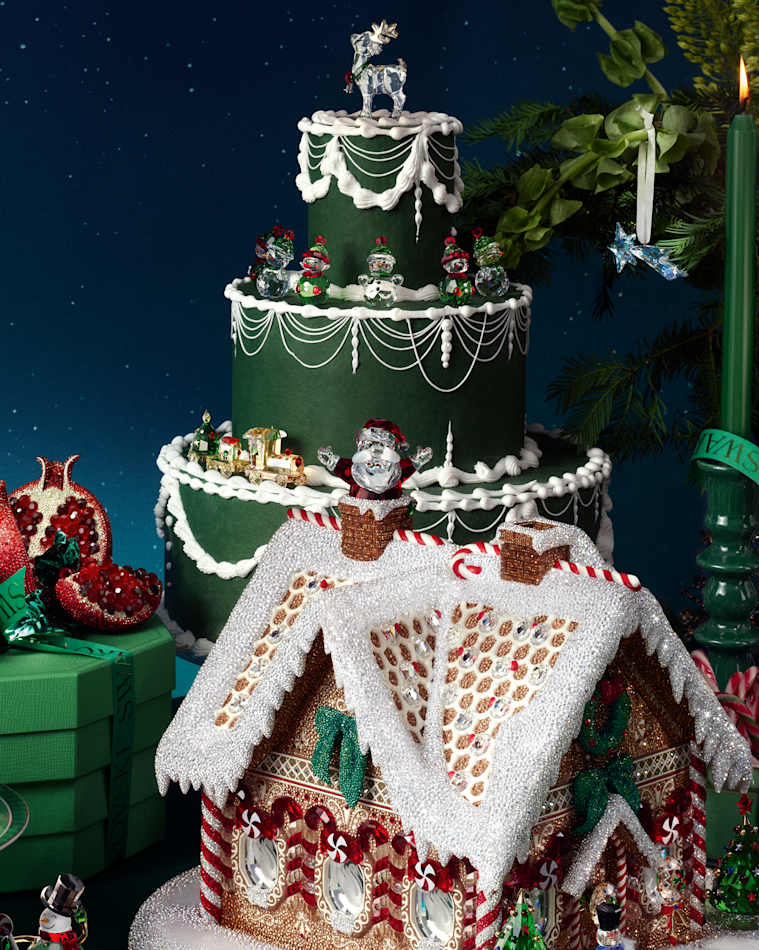 Swarovski crystal gingerbread house and tiered cake surrounded by festive crystal decorations.
