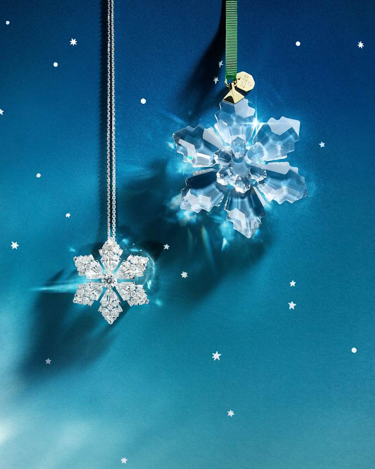 Two Annual Edition crystal snowflake pendant ornaments hanging against a starry blue background.