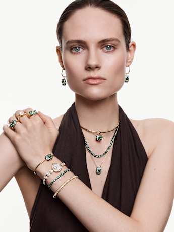 Combinación de pulseras verdes y doradas con reloj de joyería Swarovski