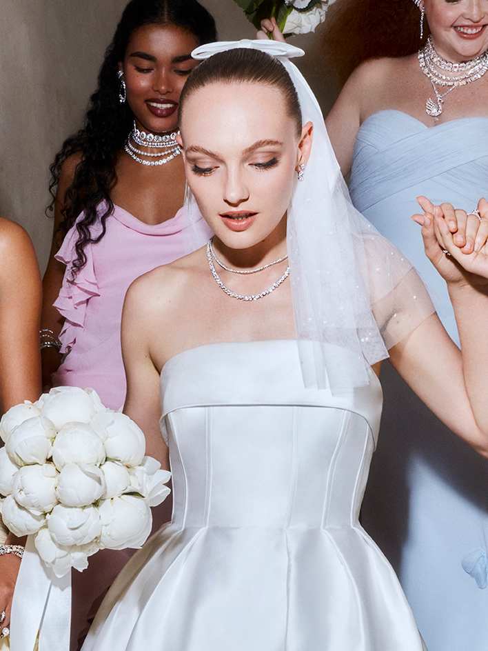 Model in weißer Maßkleidung trägt elegante Swarovski Ohrringe mit klaren Kristallen.