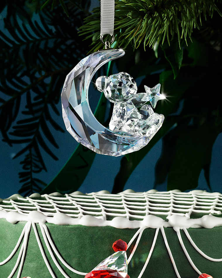 Swarovski Kris Bear Moon Ornament hanging on a festive tree.