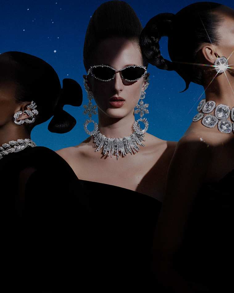 Three female models wearing clear crystal Swarovski jewelry and sunglasses against a starry sky.