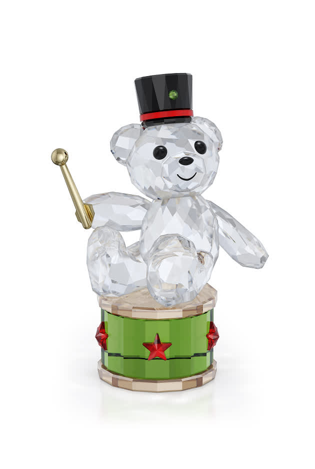 Miś Kris w czapce dobosza, siedzący z pałeczką na bębenku