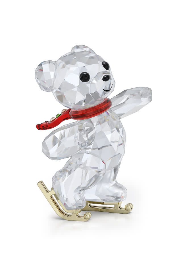 Miś Kris w czerwonym szaliku jadący na łyżwach