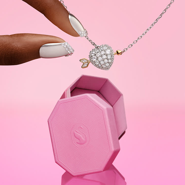 Prsty sahající po přívěsku Idyllia ve tvaru srdce