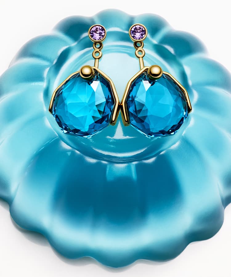Gema earrings sitting on blue jelly