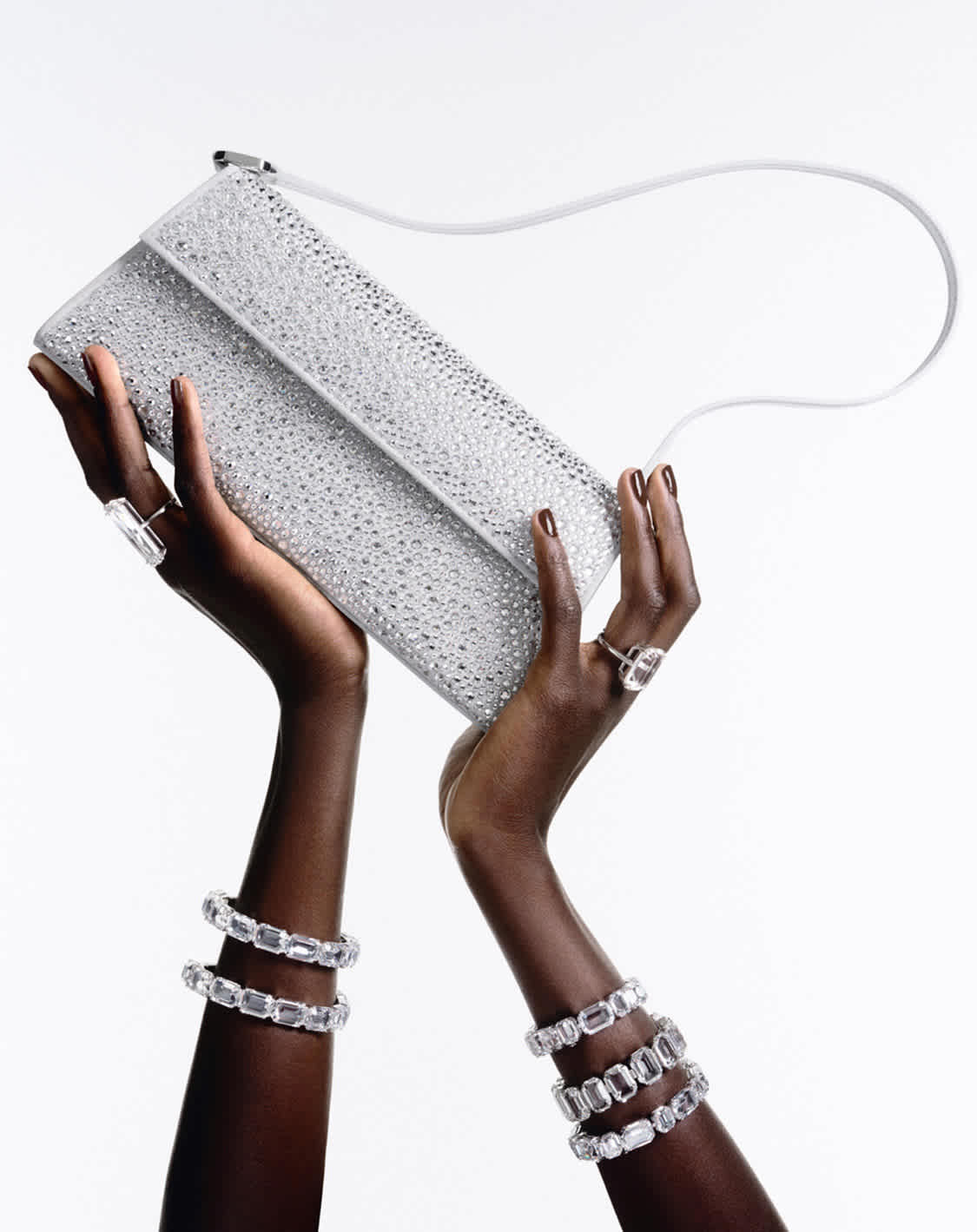 Dwie ręce trzymające torebkę Swarovski Sublima