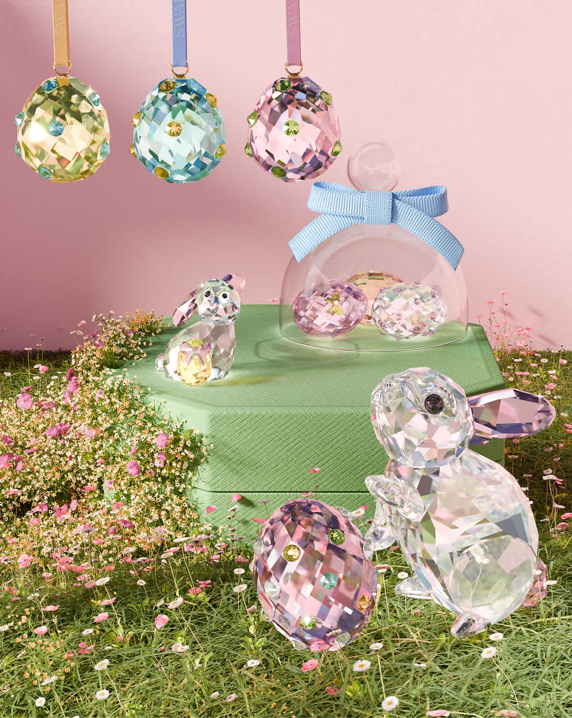 Grupa małych figurek z kolorowych kryształów Swarovskiego na różowym ośmiokątnym pudełku.